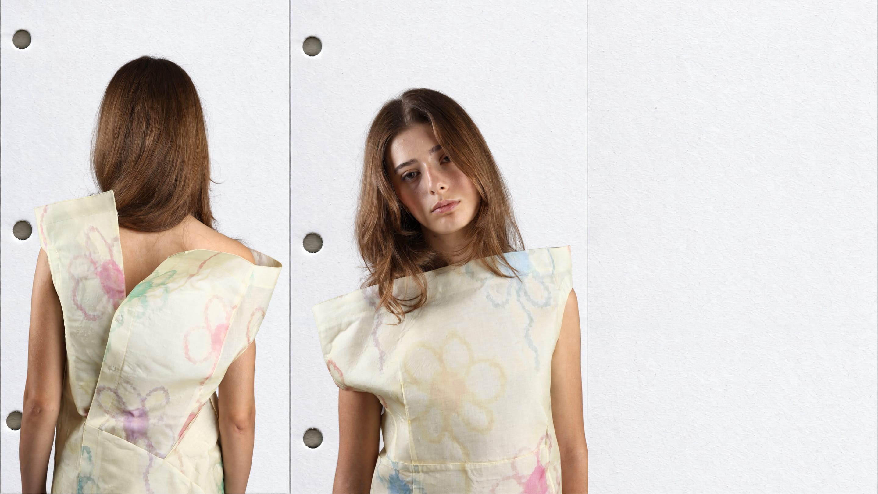 Waist-up back and front views of a model in a cream sleeveless dress with pastel hand-drawn flowers and a stiff folded panel across the back