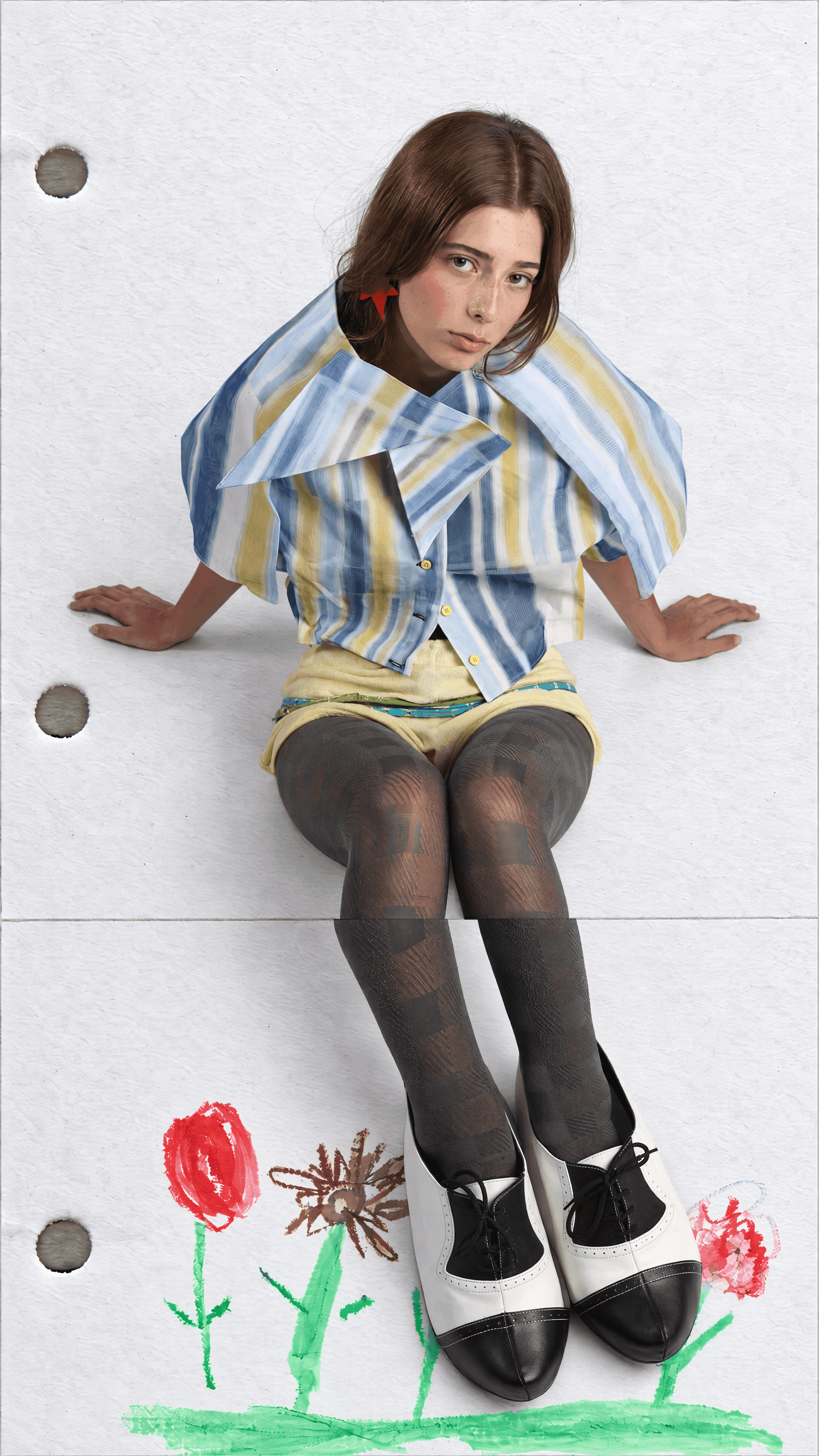 High-angle view of a model seated with legs outstretched in a blue and yellow striped oversized-collar shirt and check tights, crayon flowers around the shoes